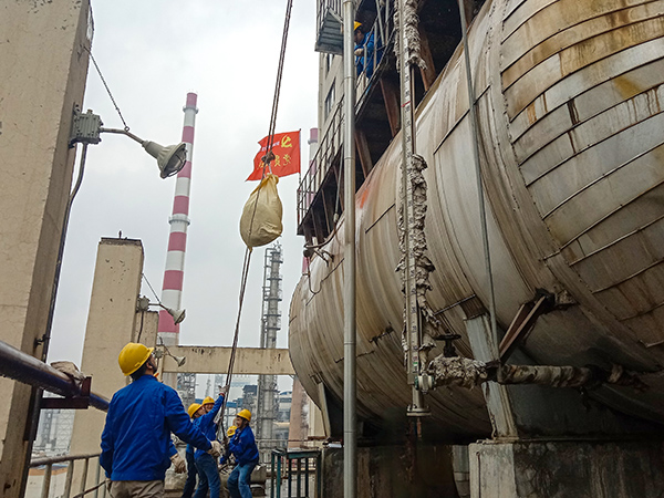 5月10日中午，在動力車間三期工藝除氧器地面，黨員突擊隊隊員用滑輪往工藝除氧器平臺運送鋼絲網(wǎng)，用以纏繞新填料.jpg