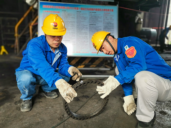 圖三：12日下午14時(shí)，在一期磨煤機(jī)廠房，陜西省技術(shù)能手姬霄給青工張跟潮講解磨煤機(jī)搖臂曲拐內(nèi)環(huán)及動(dòng)作原理。.jpg